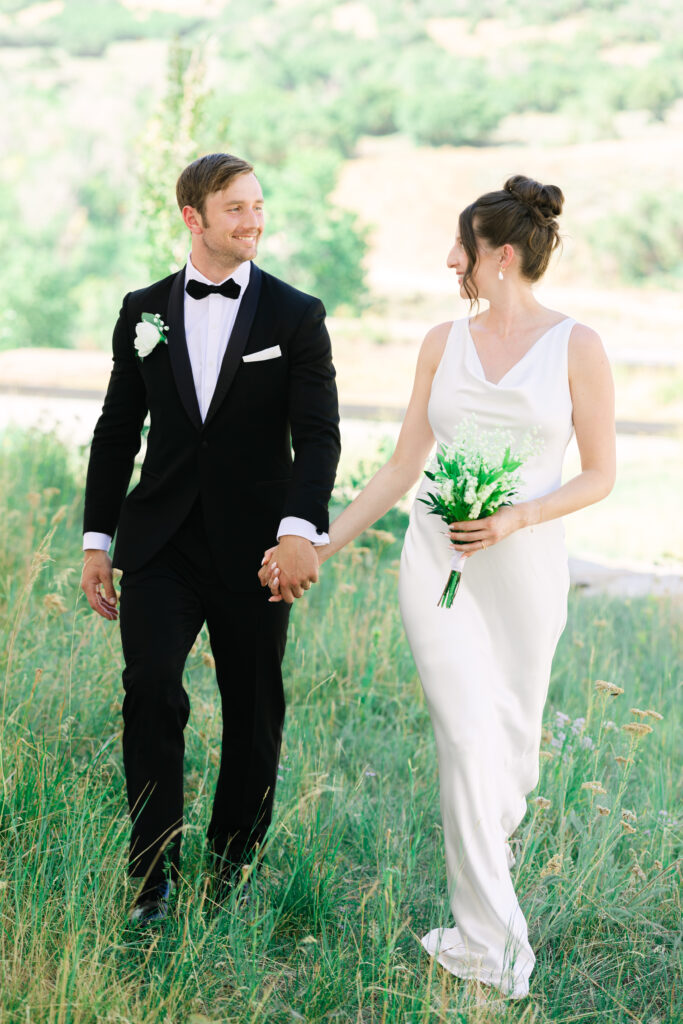 happy bride and groom walking hand in hand at the lodge at blue sky in park city
